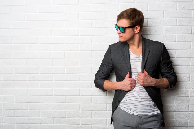 portrait-smiling-stylish-man-sunglasses-standing-against-brick-wall-modern-office_273443-3553